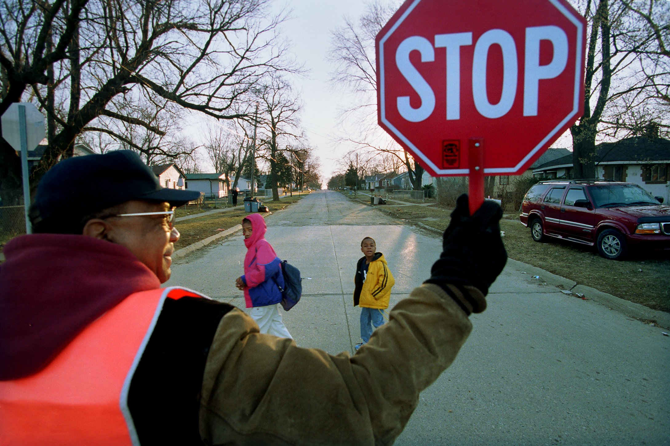 Students walk back to Buell Elementary School, helped by crossing guard Benjamin Bryant at Downey and Detroit Streets, on Monday March 6, 2000. It was the first day back after the fatal shooting of first grader Kayla Rolland by another first grade student. (Flint Journal File Photo by Steve Jessmore)