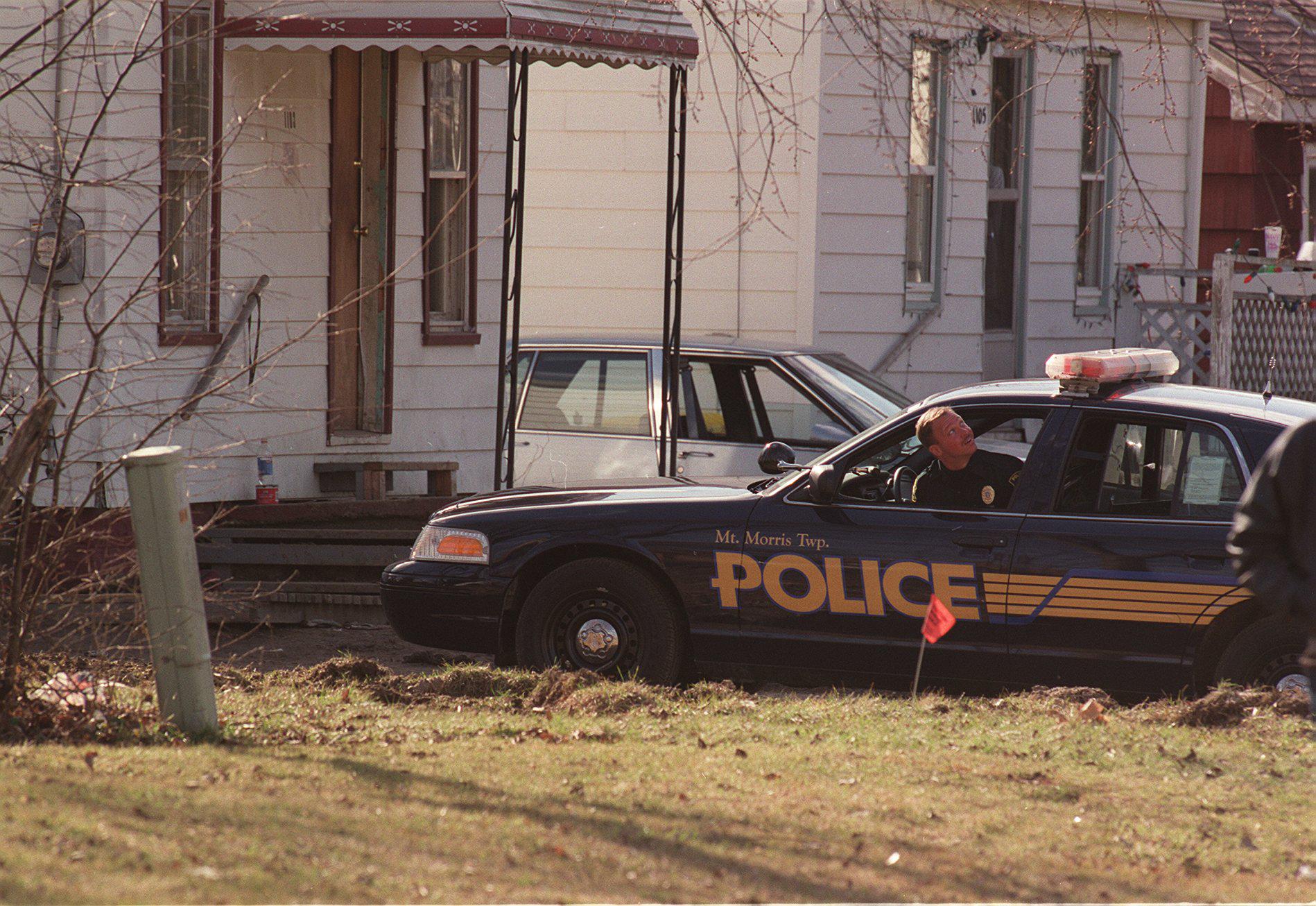 A Mt. Morris police officer looks to the sky Tuesday afternoon, Feb. 29, 2000 after hearing the sound of a helicopter overhead. The cruiser was stationed at 1103 W. Juliah, where it is alleged that the shooter got the gun he used at Buell Elementary. (Flint Journal File Photo by Jane Hale)