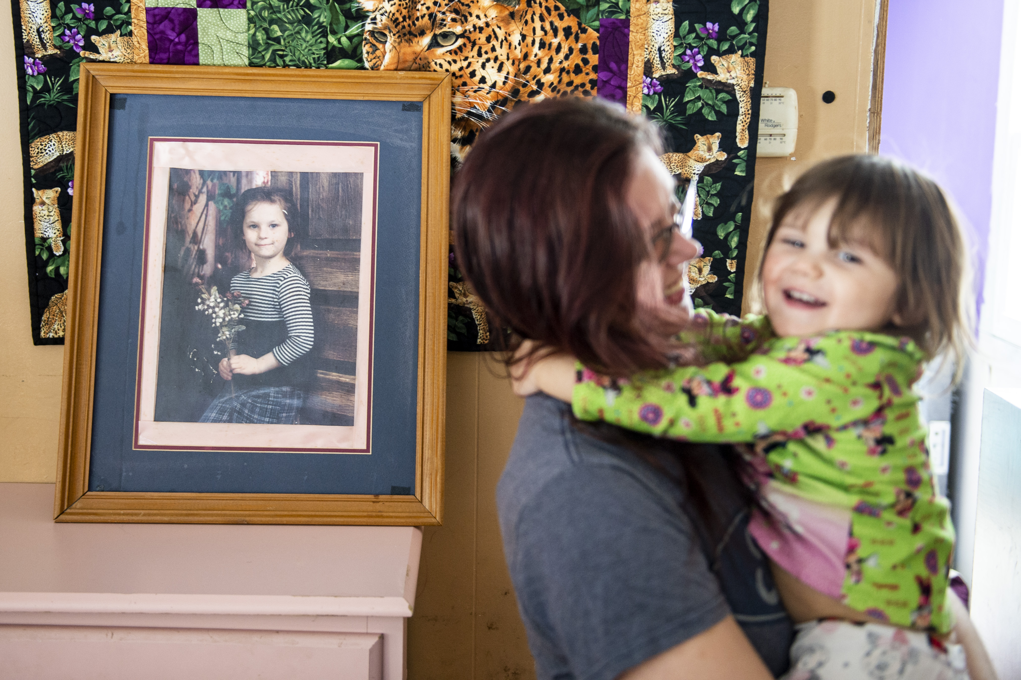 Elizabeth Krasinski and her daughter Savannah Krasinski, 2, pose for a photograph in Tawas City on Thursday, Feb. 20, 2020. Elizabeth lost her sister, Kayla Rolland (pictured in the frame), 20 years ago in a school shooting when Rolland was only in first grade. In 2000, the story made national news as Rolland is amongst the youngest of school shooting victims.