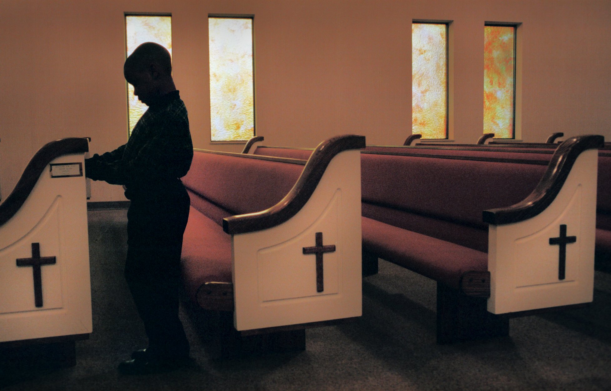Jevon Calland, 7, prays at the beginning of a series of revival meetings which were intended to rejuvenate the Beecher community following the shooting death of Kayla Rolland at Buell Elementary School. Photo at the Greater Friendship Azuza Church in Mt. Morris Township on Sunday, March 25, 2000. (Flint Journal File Photo by Justin Warren)