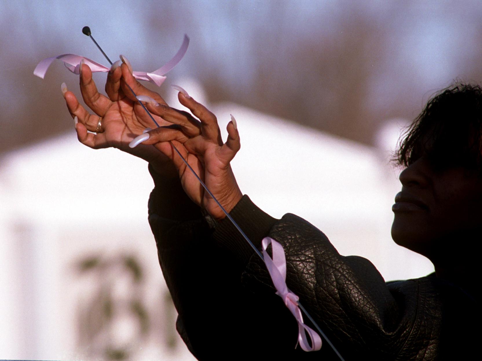 Linda Jones of Flint ties a pink ribbon on her car antenna Friday morning, March 3, 2000, after attending visitation for six year old Kayla Rolland at Brown Funeral Home. (Flint Journal File Photo by Jane Hale)
