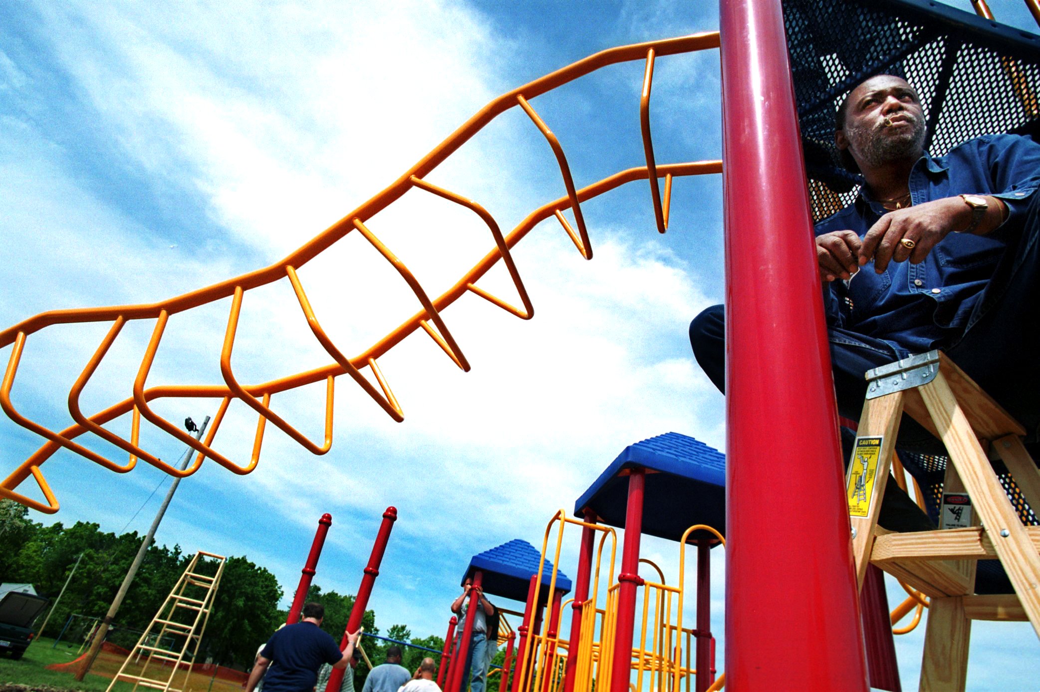 Flint resident Lawrence Warren waits for a cement truck to deliver a load of concrete to shore up the pilings of the new play structure that he and several dozen others worked to install at Buell Elementary School in honor of first-grade shooting victim Kayla Rolland on Friday, May 26, 2000. (Flint Journal File Photo by Justin Warren)